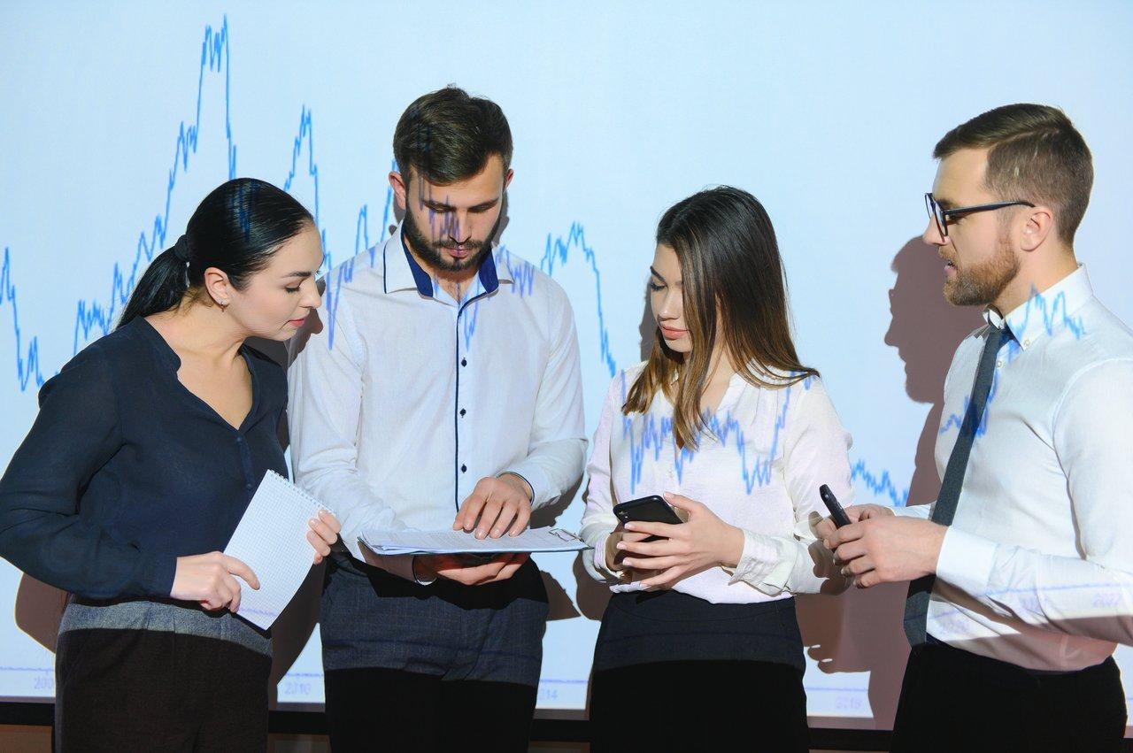 Réunion commerciale entre six professionnels analysant des graphiques financiers pour évaluer le coût en temps et ressources.